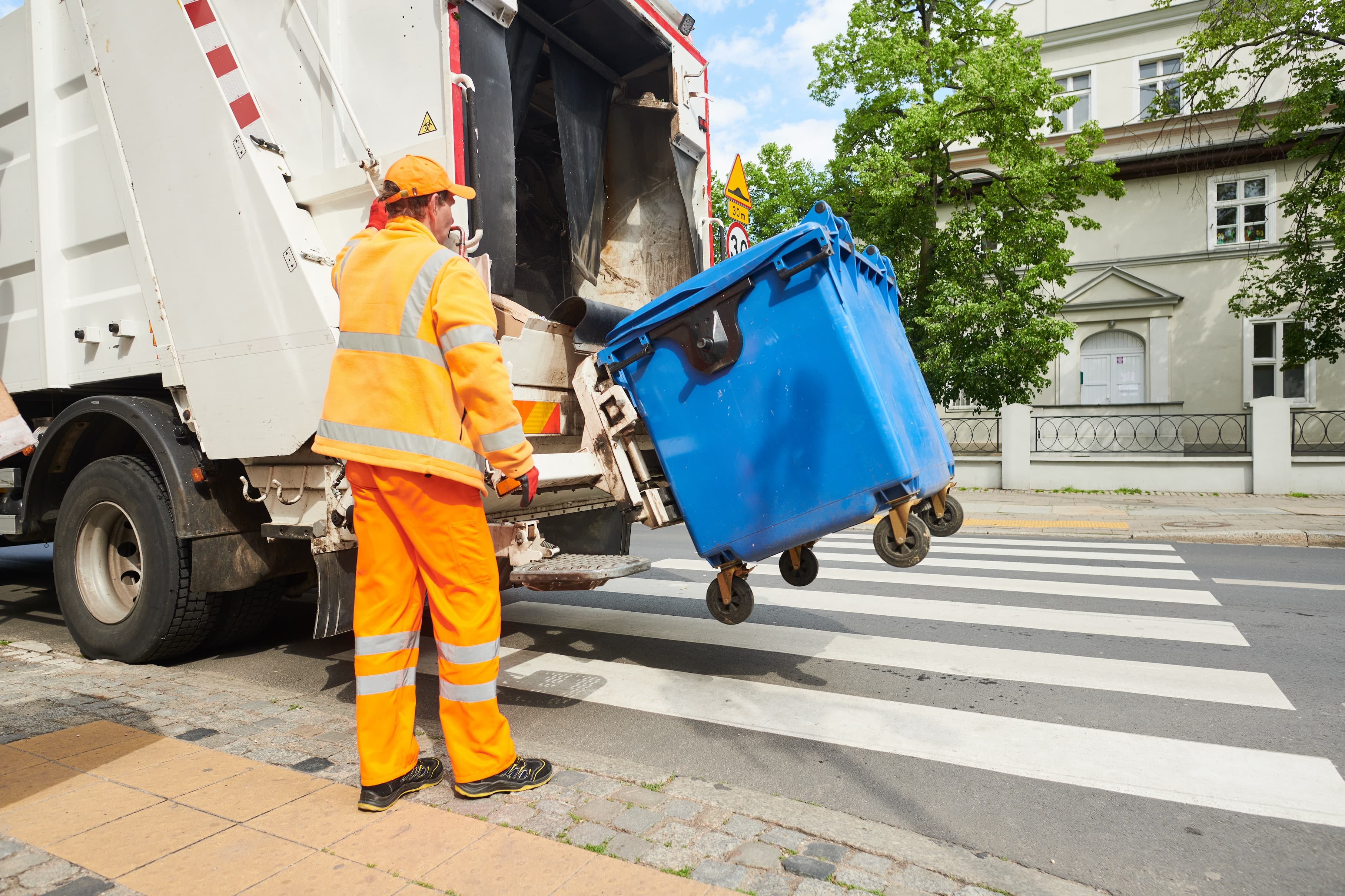 Professional refuse worker servicing a wheeled bin at a collection vehicle